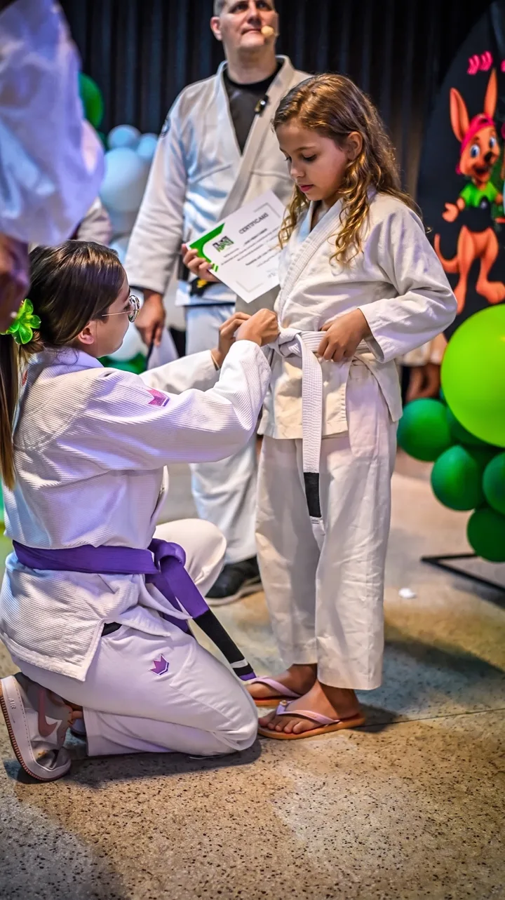 Professora ajustando a faixa de uma aluna na cerimônia de graduação